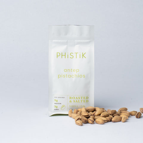 White bag labeled 'PHISTIK' with pistachios on a light gray background