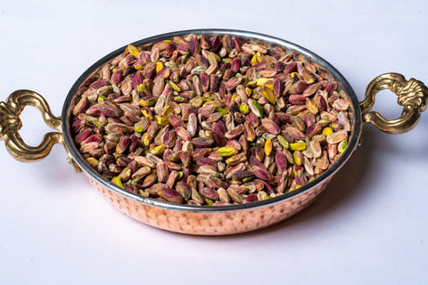Copper bowl with antep pistachios on a white background